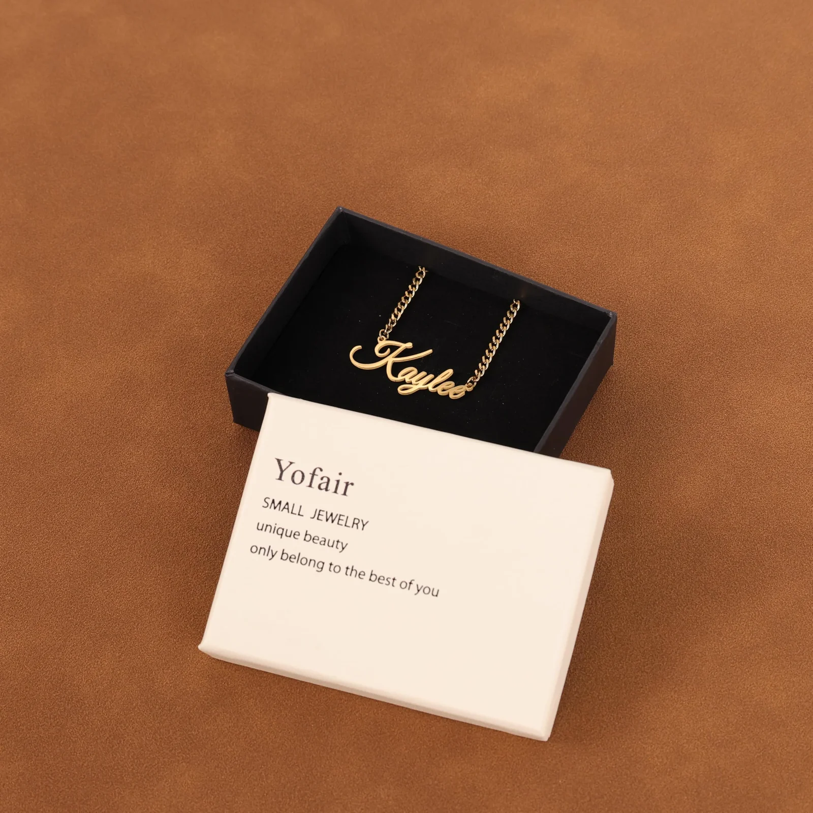 A gold nameplate in an open white box with a printed card beside it